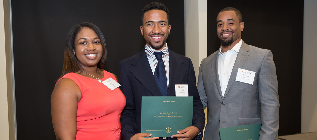 A student posing with scholarship along side two representatives from the Black Alumni Society